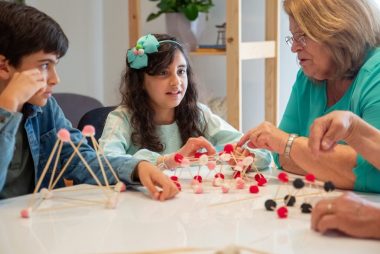 Grandmother playing educational games with grandchildren indoors, fostering creativity and learning.