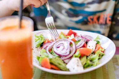 Colorful salad with fresh vegetables and a refreshing drink on a table.